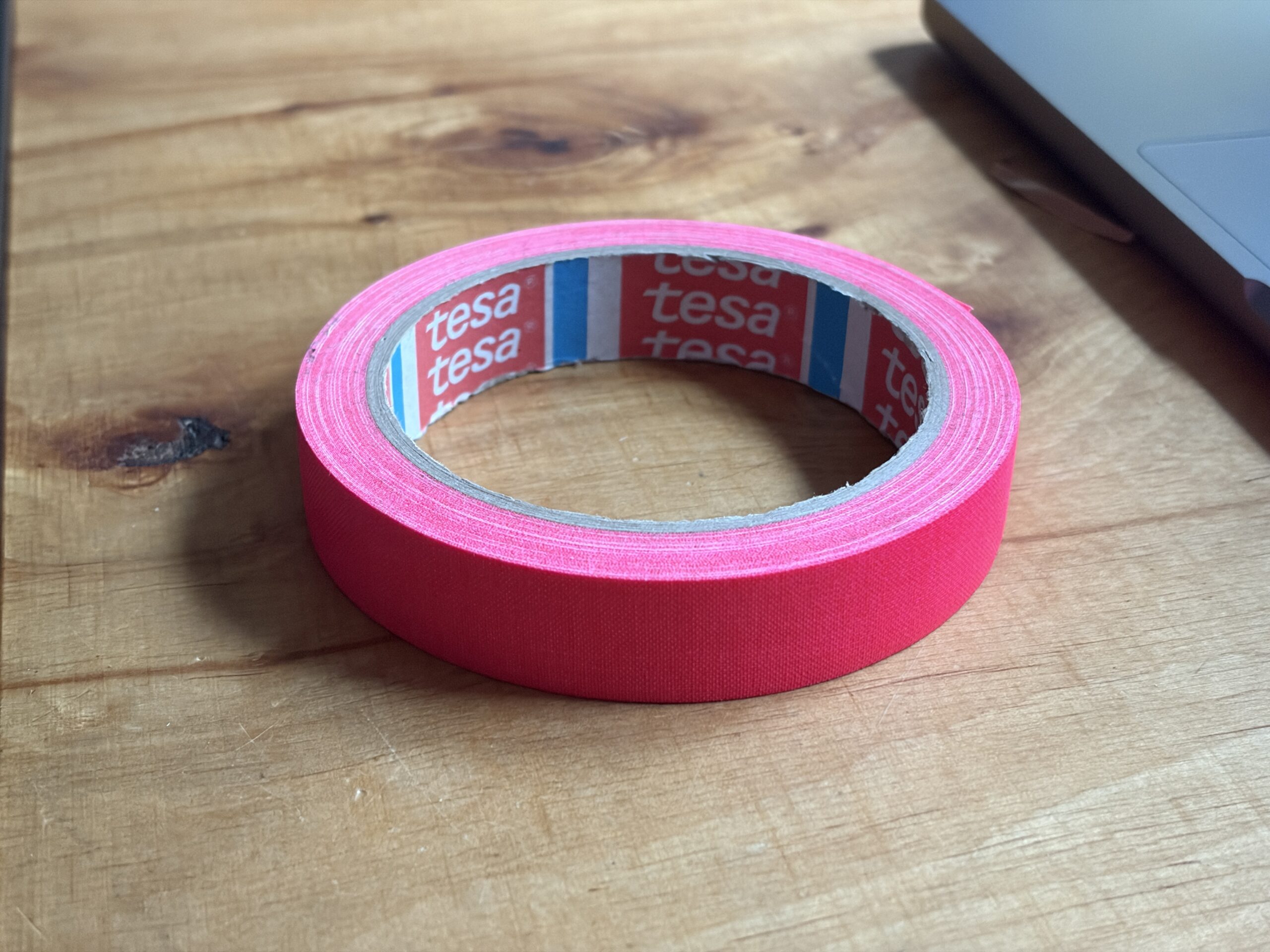 Rolle pinkes Tesa-Gewebeband auf einem Holztisch