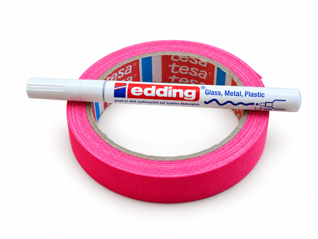 Weißer Edding auf einer Rolle pinkem Gewebeband vor weißem Hintergrund.